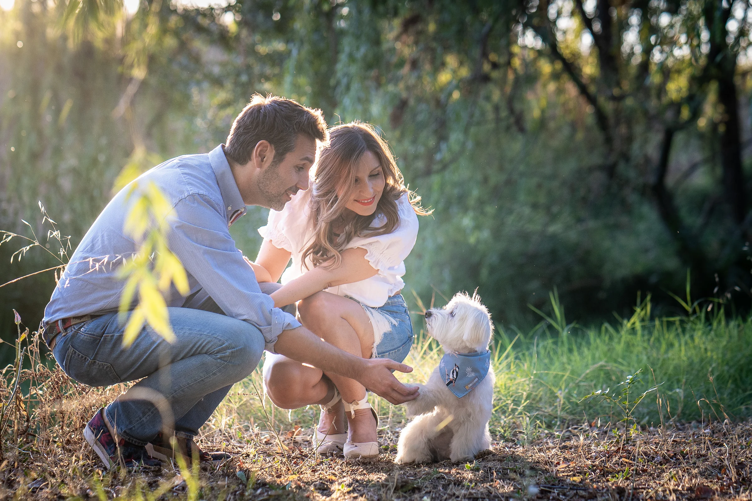 Vanesa y Fran juegan con su perro en el césped durante su sesión de preboda en Madrid.