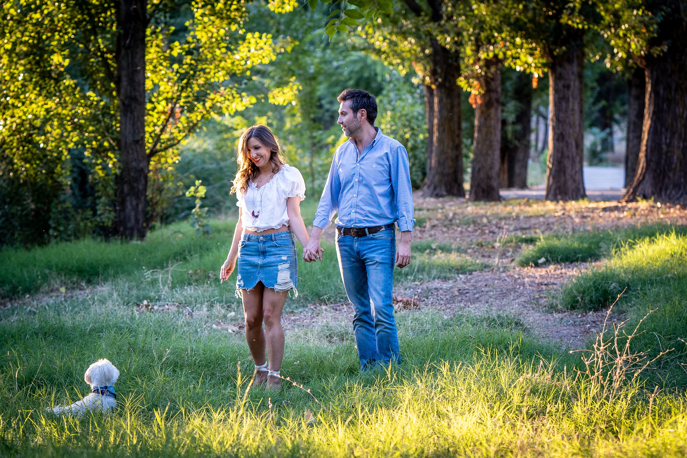 Vanesa y Fran pasean con su perro por una pradera del parque durante su preboda en Madrid.