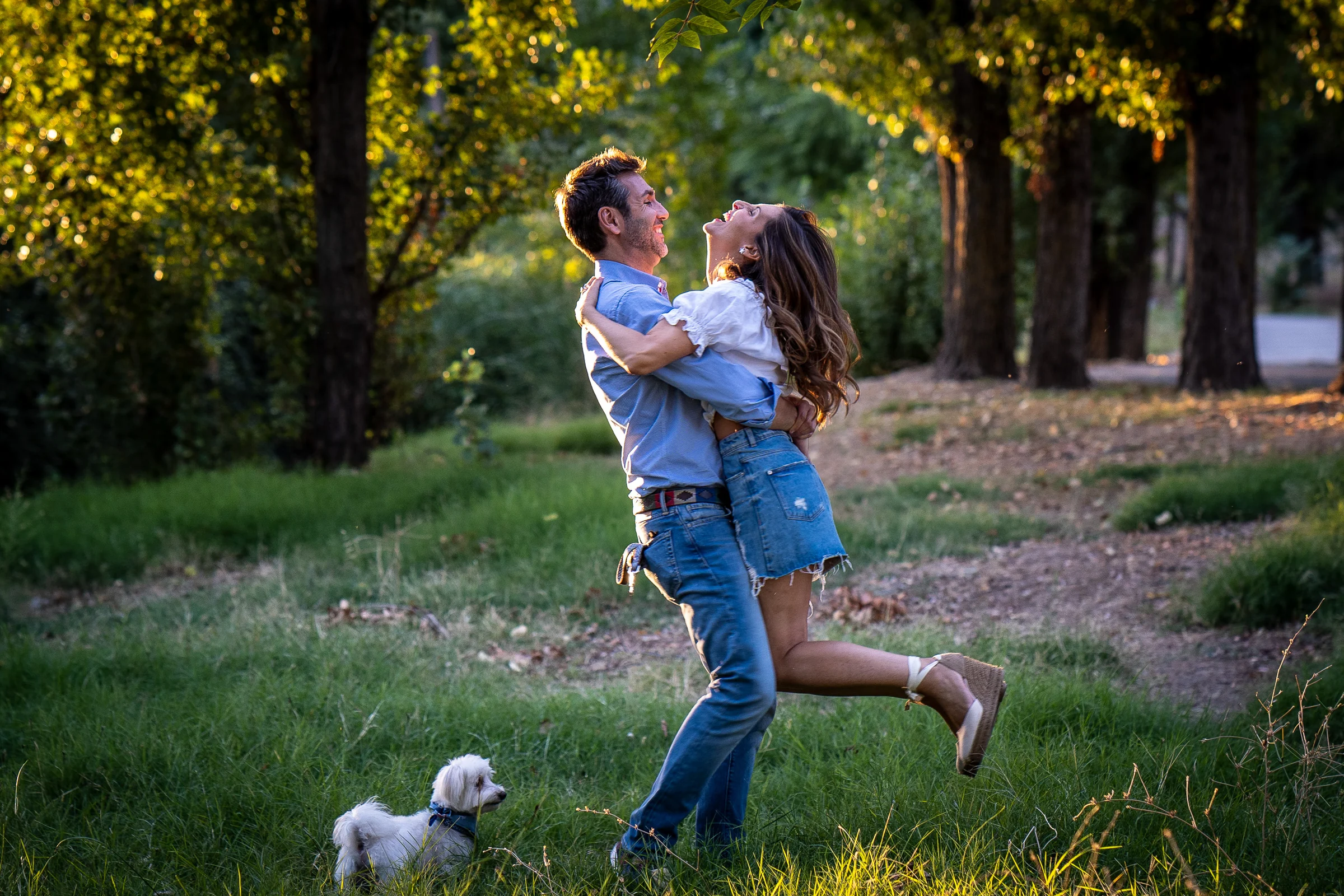 Vanesa y Fran se abrazan y juegan en una pradera del parque durante su preboda en Madrid.