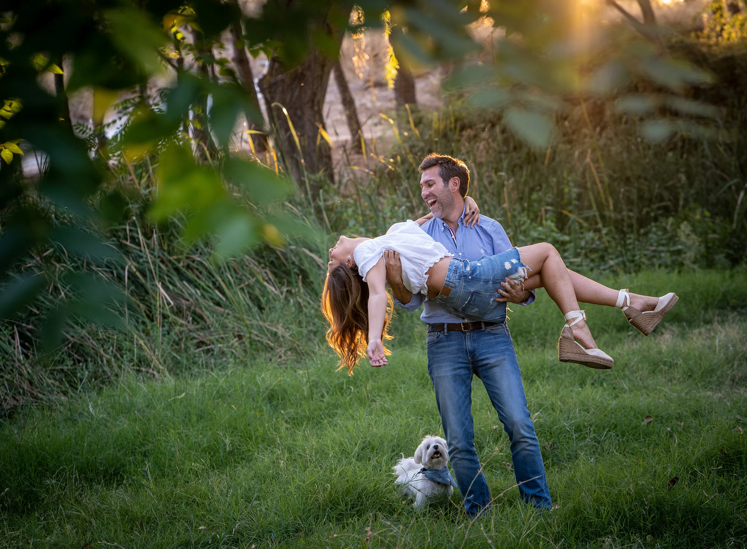 Fran sostiene a Vanesa en brazos mientras ambos sonríen durante su preboda en el parque de Madrid.